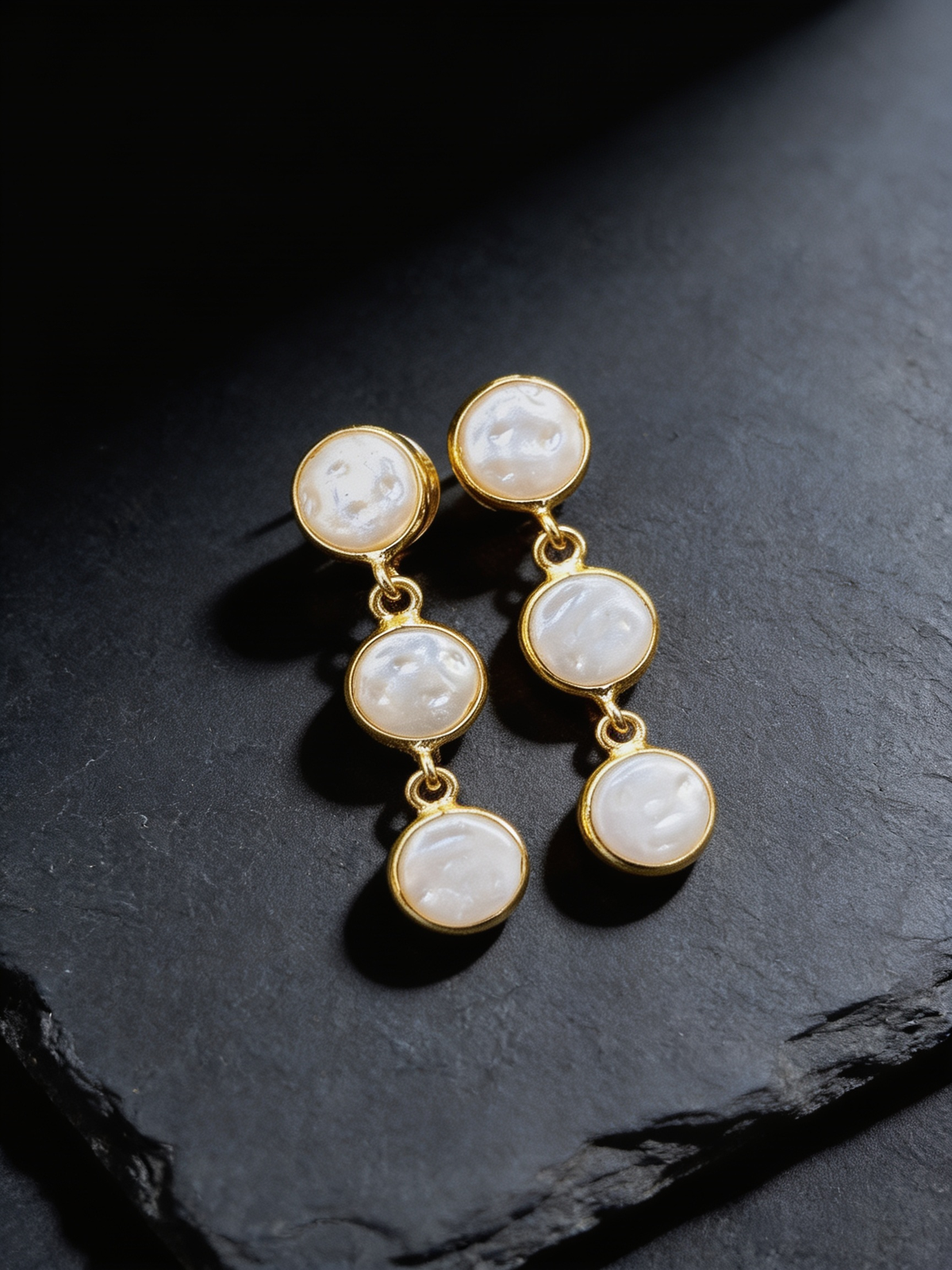 Trio pearl stud earrings on a dark background